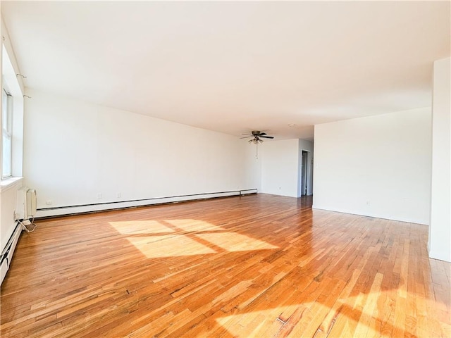 unfurnished room with a baseboard radiator, a ceiling fan, and wood finished floors