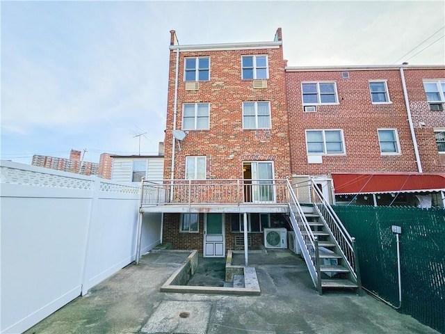 back of property with ac unit, brick siding, a deck, stairway, and a fenced backyard