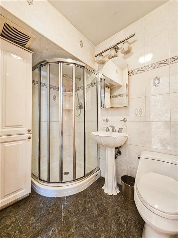 bathroom featuring toilet, tile walls, visible vents, and a stall shower