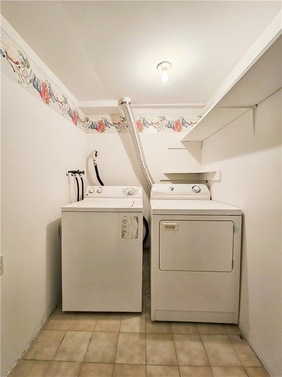 clothes washing area with light tile patterned floors, laundry area, and washer and clothes dryer