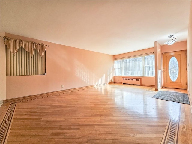foyer featuring radiator heating unit, baseboards, and wood finished floors