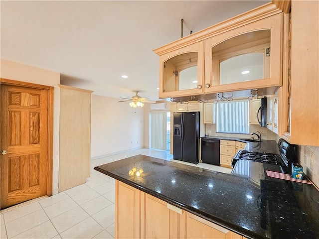 kitchen with dark stone countertops, a peninsula, light tile patterned floors, backsplash, and black appliances