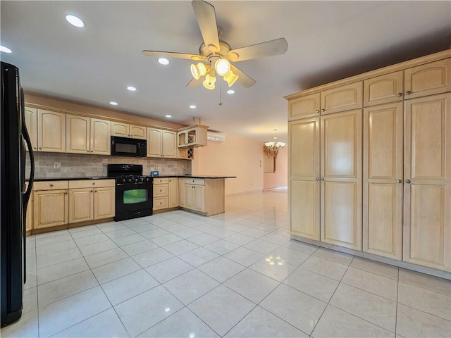 kitchen with light brown cabinetry, dark countertops, ceiling fan with notable chandelier, decorative backsplash, and black appliances
