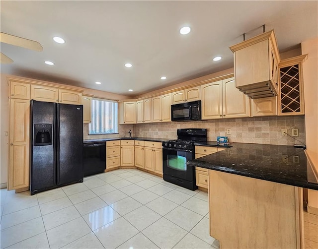 kitchen with light brown cabinetry, tasteful backsplash, a sink, black appliances, and a peninsula