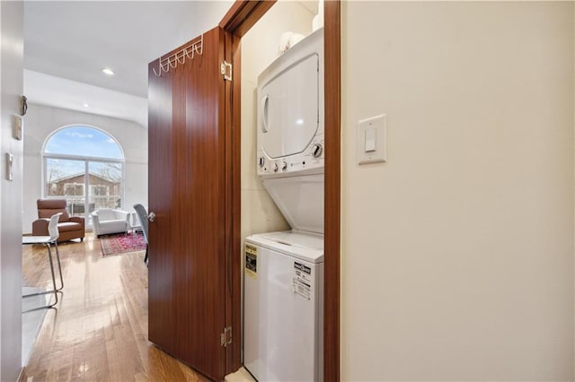 laundry area with stacked washer and clothes dryer, recessed lighting, light wood finished floors, and laundry area