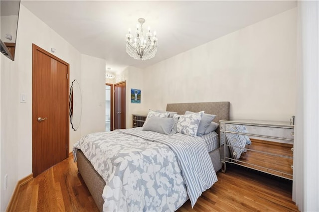 bedroom with an inviting chandelier and wood finished floors