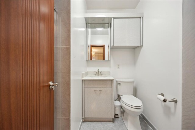 bathroom with toilet, tile patterned flooring, vanity, and baseboards