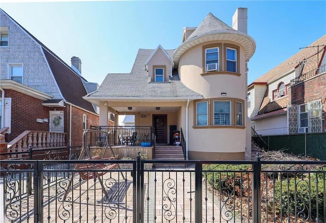 view of front of home with a fenced front yard, roof with shingles, and stucco siding