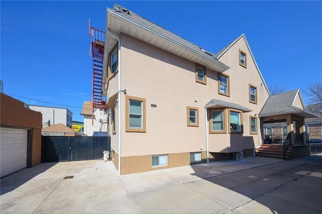 rear view of property featuring stucco siding and fence