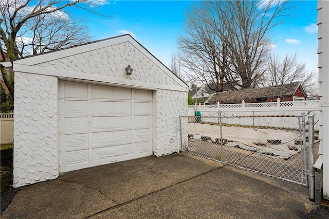 detached garage with fence and concrete driveway