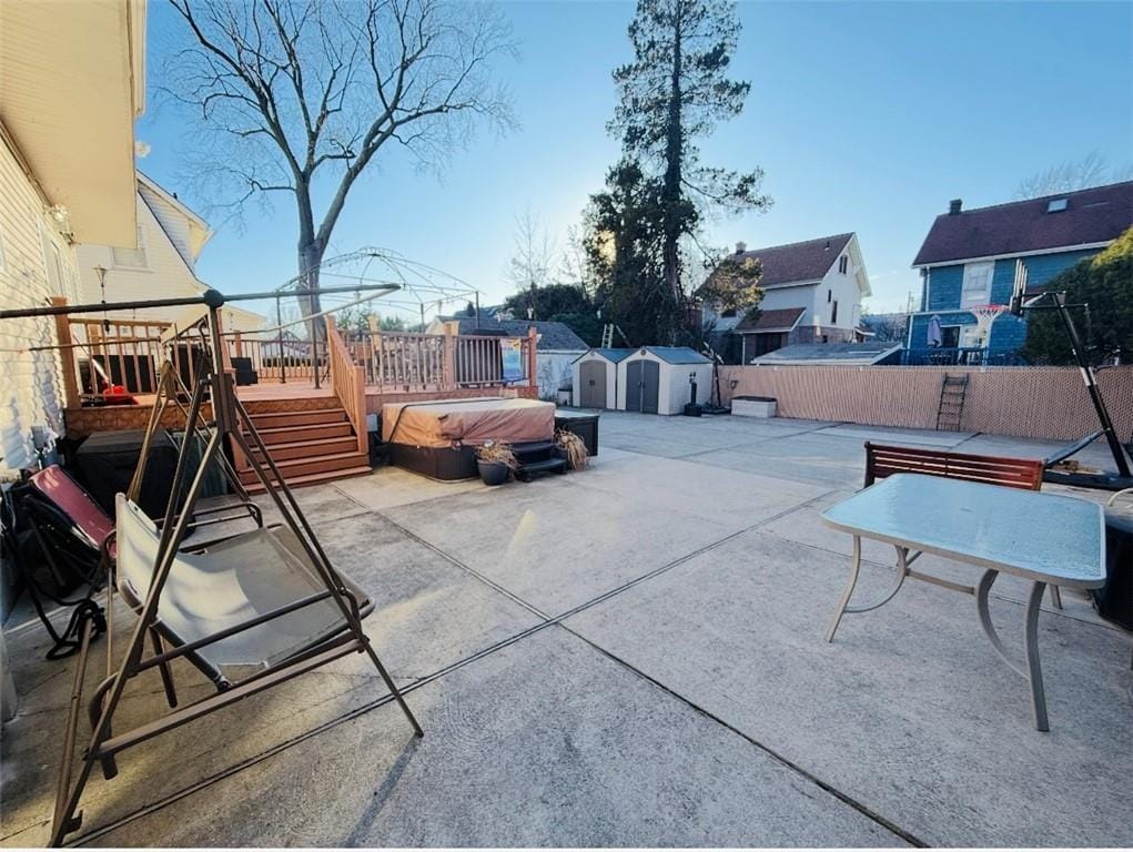 view of patio featuring an outbuilding, a shed, fence, and a wooden deck