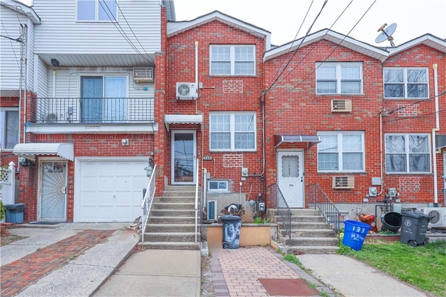 townhome / multi-family property with an attached garage, brick siding, and driveway