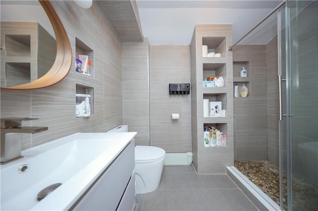 bathroom with tile walls, tile patterned flooring, a stall shower, vanity, and toilet