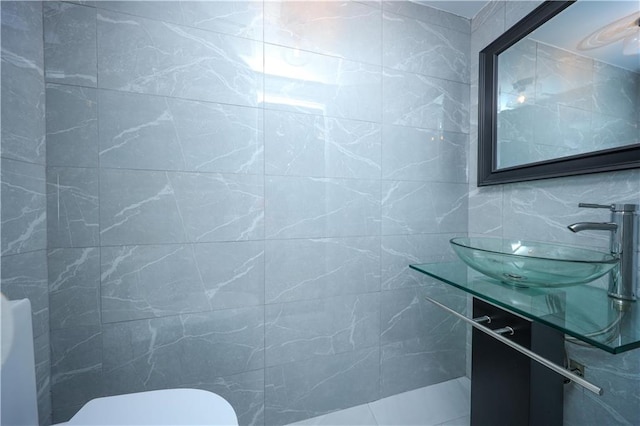bathroom with tile walls, a sink, and toilet