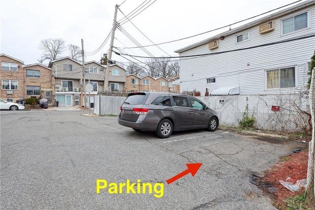 view of parking featuring fence and a residential view
