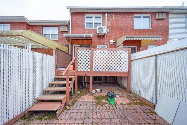 back of house with brick siding, fence, a cooling unit, a deck, and a wall mounted air conditioner