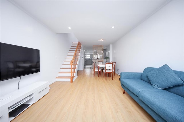 living area featuring stairway, light wood-style floors, recessed lighting, baseboards, and a chandelier