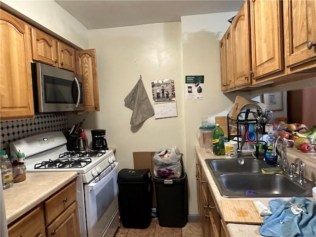 kitchen with gas range gas stove, stainless steel microwave, light countertops, brown cabinets, and a sink