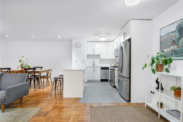 kitchen with a breakfast bar, light countertops, white cabinets, stainless steel appliances, and a sink