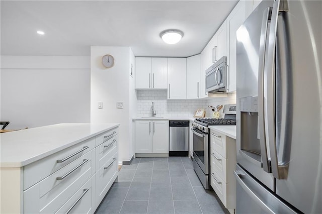 kitchen featuring a sink, white cabinetry, stainless steel appliances, decorative backsplash, and light tile patterned flooring