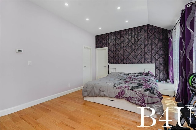 bedroom featuring recessed lighting, wood finished floors, vaulted ceiling, baseboards, and an accent wall