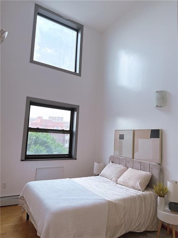 31-47 137th St Unit 4B, Brooklyn, NY 11354 - bedroom featuring a baseboard heating unit and wood finished floors