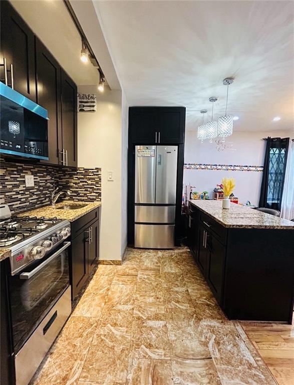 2807 Kings Hwy Unit 4C, Brooklyn, NY 11229 - kitchen featuring appliances with stainless steel finishes, dark cabinetry, a sink, and light stone counters