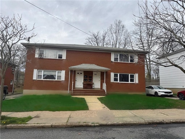 view of front facade with brick siding and a front yard
