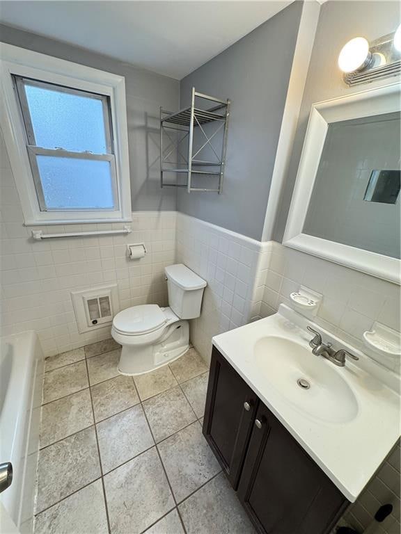 bathroom featuring vanity, toilet, tile walls, a bathtub, and tile patterned floors