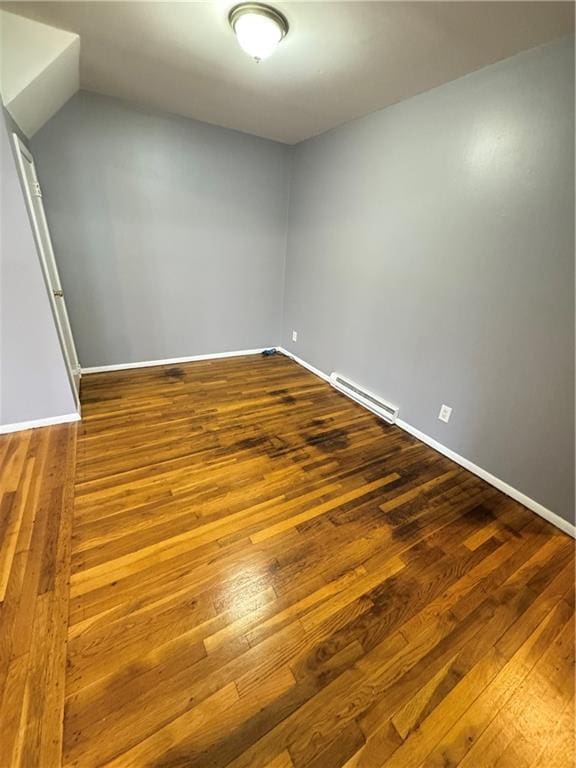 spare room featuring baseboards, a baseboard radiator, and wood finished floors