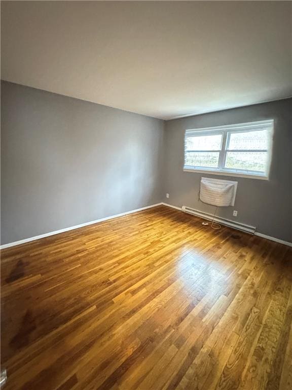unfurnished room with baseboards, a baseboard radiator, and dark wood-style flooring