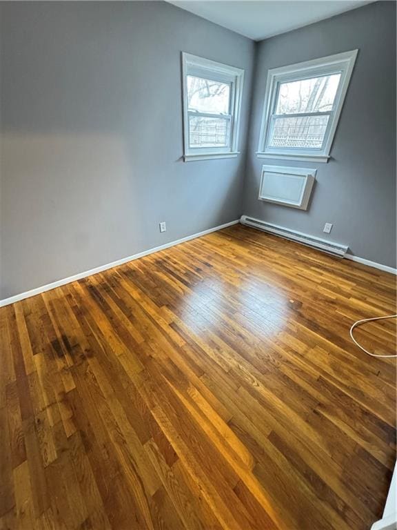 unfurnished room with baseboards, baseboard heating, and wood finished floors