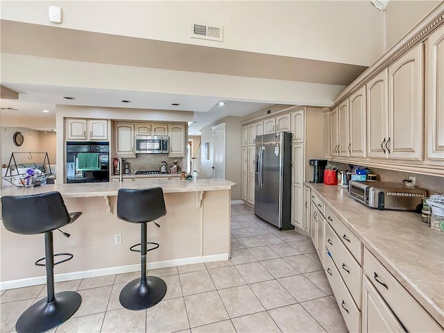 kitchen featuring light tile patterned floors, a kitchen breakfast bar, visible vents, and stainless steel appliances