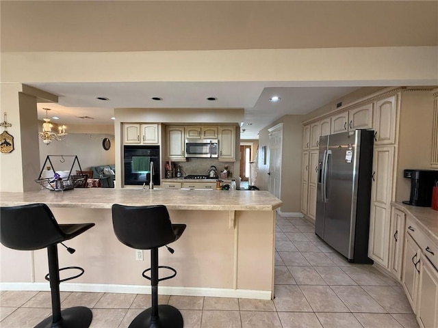 kitchen featuring light tile patterned floors, a kitchen breakfast bar, light countertops, and appliances with stainless steel finishes