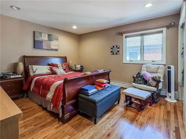 bedroom featuring light wood-style flooring, a baseboard heating unit, and recessed lighting
