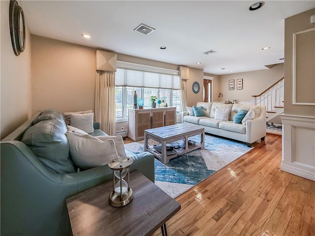 living area featuring visible vents, light wood-style flooring, stairway, and recessed lighting