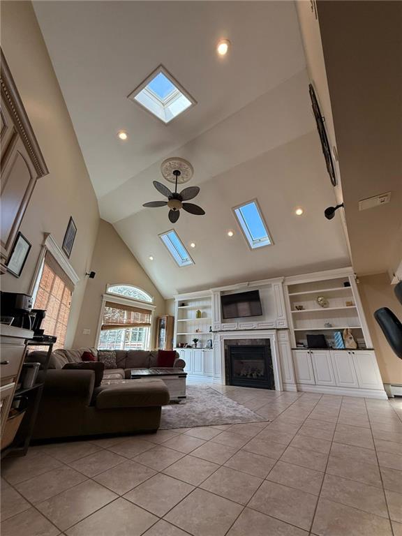 living area with recessed lighting, light tile patterned floors, a ceiling fan, a skylight, and high vaulted ceiling