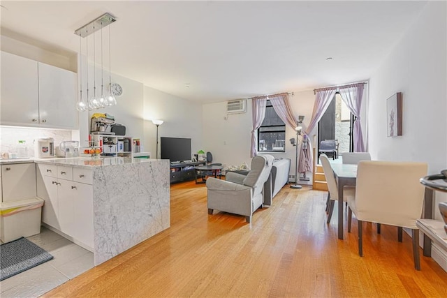 kitchen with white cabinets, a peninsula, light wood-type flooring, open floor plan, and hanging light fixtures