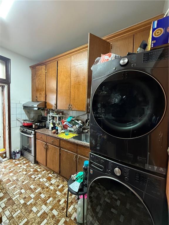 laundry area with stacked washer and clothes dryer, a sink, and laundry area