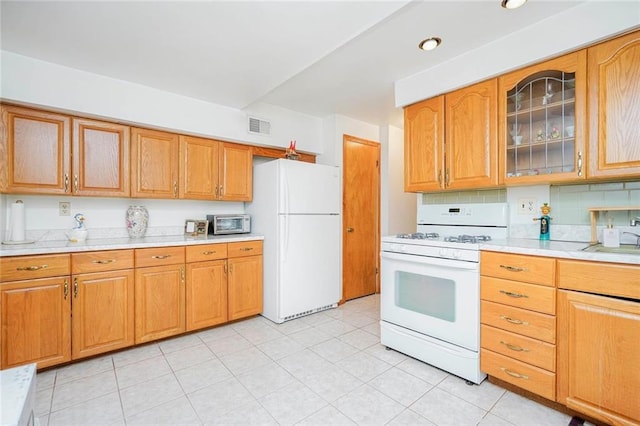 kitchen with visible vents, white appliances, glass insert cabinets, and light countertops