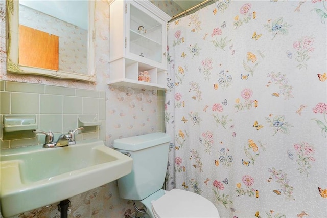 full bath with curtained shower, toilet, decorative backsplash, and a sink