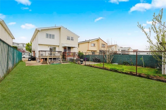 back of house featuring a lawn, a wooden deck, fence, and a residential view
