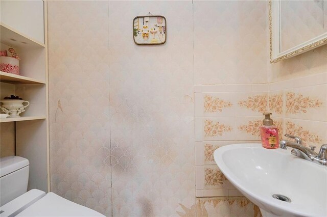 bathroom with tile walls, toilet, and a sink