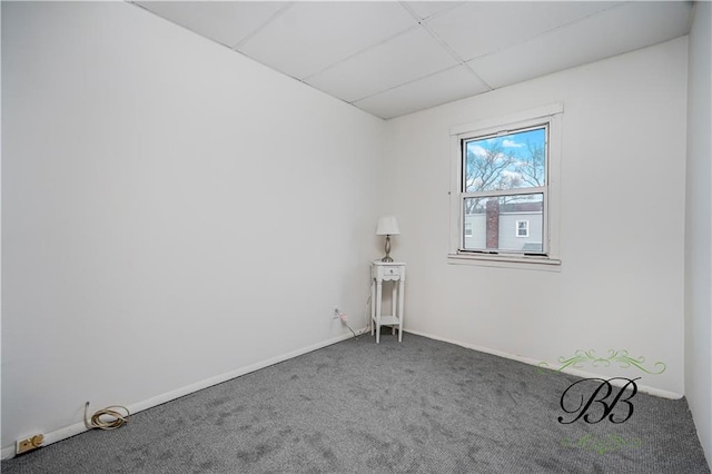 empty room with baseboards, a paneled ceiling, and carpet