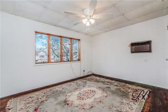 empty room featuring baseboards, a drop ceiling, ceiling fan, and wood finished floors
