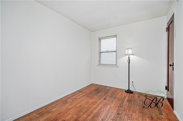 unfurnished room with baseboards and wood-type flooring
