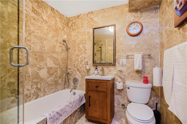 bathroom with tile walls, tiled shower / bath combo, toilet, and vanity