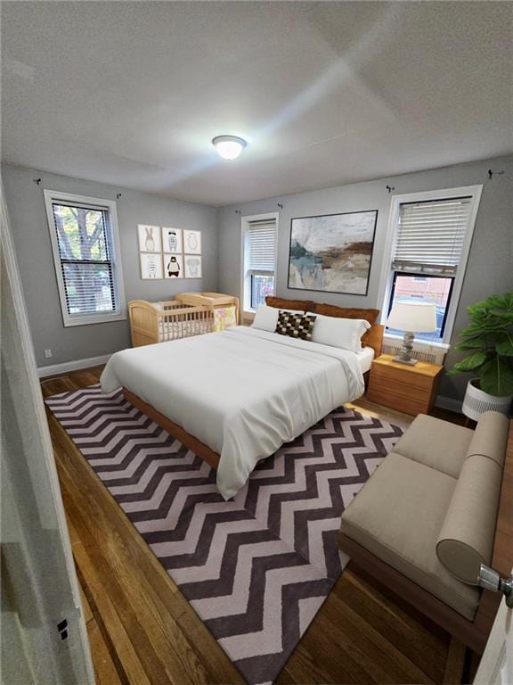 bedroom with a textured ceiling, baseboards, and wood finished floors