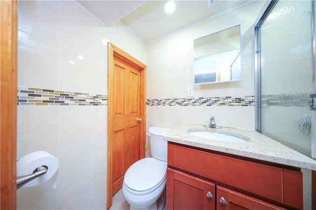 bathroom featuring toilet, vanity, and tile walls