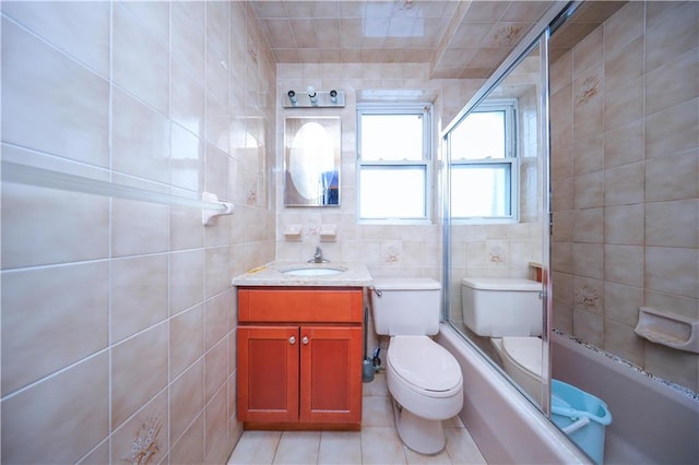 full bath with tile patterned flooring, tile walls, toilet, vanity, and tub / shower combination